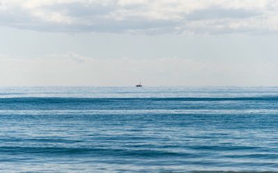 Distance shot of boat in calm sea against sky