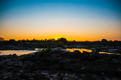 Scenic view of beach against clear sky at sunset