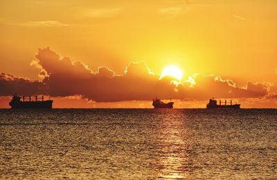 Silhouette boats on sea against sky during sunset