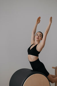 Portrait of young woman exercising against wall