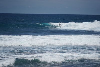 Man surfing in sea against sky