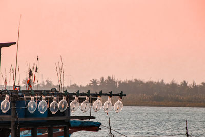 Fishing boat moored in sea against clear punk sky during sunset