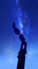 Low angle view of silhouette statue against blue sky