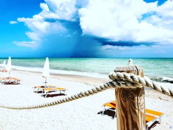 Deck chairs on beach against sky