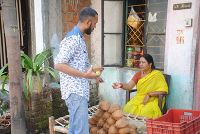 Man purchasing coconut from woman at market