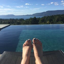 Low section of woman against infinity pool and lake