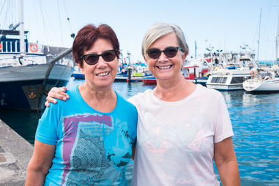 Portrait of smiling friends standing at harbor