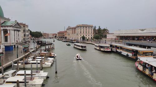 Boats in canal amidst buildings in city against sky