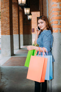 Young woman holding smart phone while standing outdoors