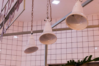 Low angle view of illuminated light bulb hanging on ceiling