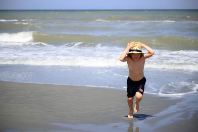 Full length of shirtless boy on beach