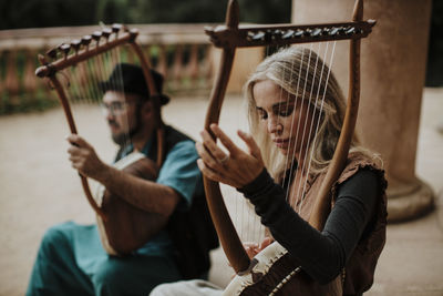 Female with male partner playing lyra instrument on staircase