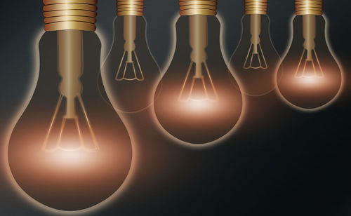 Close-up of illuminated light bulb hanging on table