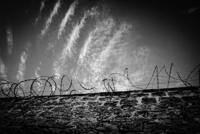 Close-up of barbed wire fence against sky