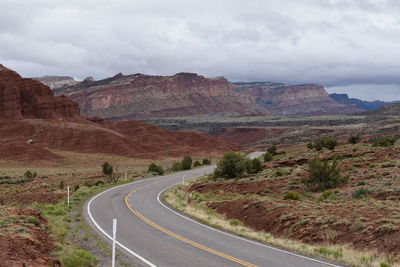 Road leading towards mountains against sky