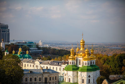 Beautiful yellow and gold domes of the orthodox church against the of the blue sky and the city.