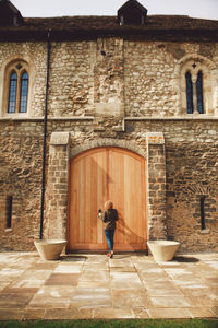 Rear view of woman standing in front of closed old building