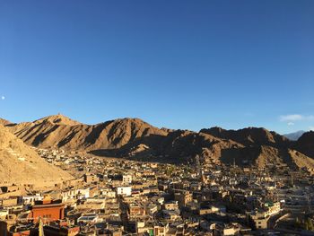 Aerial view of townscape and mountains against clear blue sky