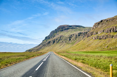 Road leading towards mountains against sky