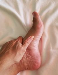 Close-up of human hand on bed