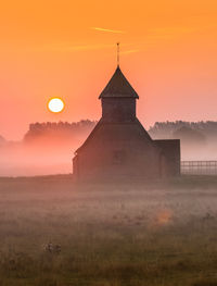 Tower on field against orange sky