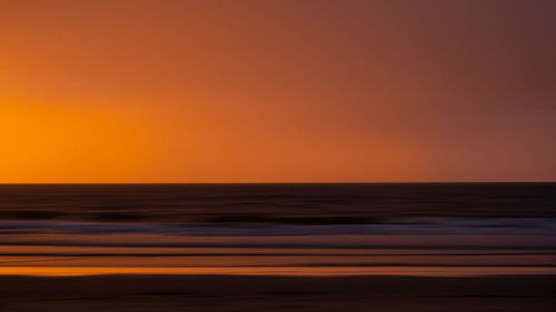 Scenic view of sea against orange sky