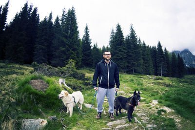 Full length of man with dog standing against trees
