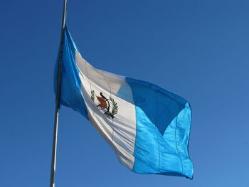 Low angle view of flag against clear blue sky