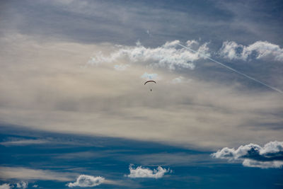 Low angle view of paragliding over sea against sky