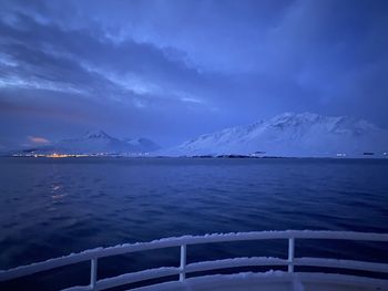 Scenic view of sea by snowcapped mountain against sky