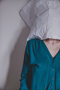 Woman covering face standing by wall at home