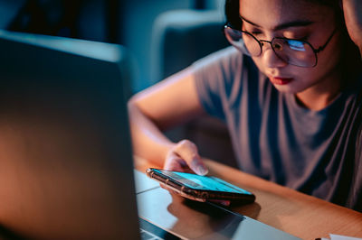 Midsection of woman using mobile phone while sitting on table