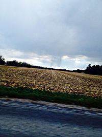 Scenic view of field against cloudy sky