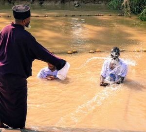 Rear view of father with daughter in water