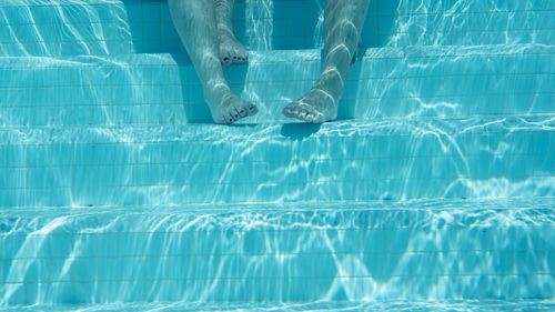 Low section of person swimming in pool