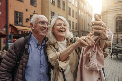 Happy senior woman taking selfie with man in city