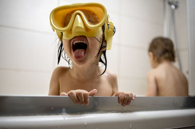 Boy wearing swimming goggles taking bath in bathroom