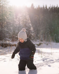 Toddler walking in the snow at a park on a sunny day