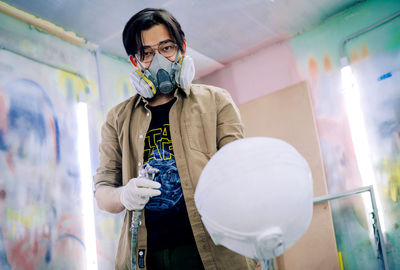 Full length portrait of young man standing against graffiti