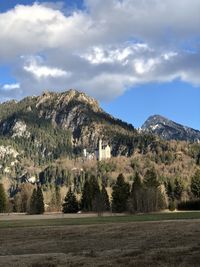 Trees on field by mountain against sky