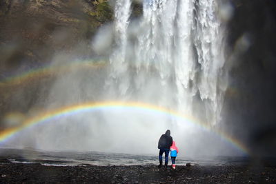 Rear view of man standing against rainbow in water