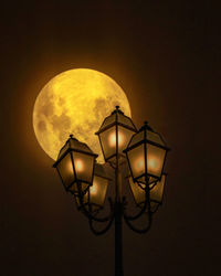 Low angle view of illuminated street light against sky