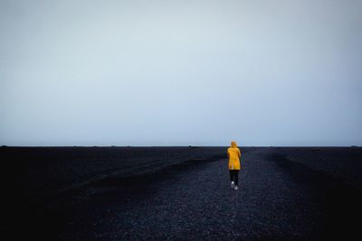 Rear view of person walking on road