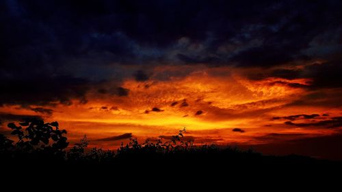 Silhouette landscape against dramatic sky during sunset