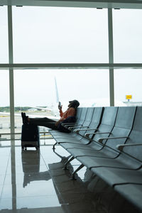 Woman checks her mobile phone while waiting for her flight at the airport.