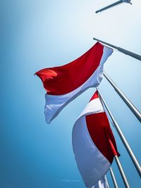 Low angle view of flag against clear blue sky