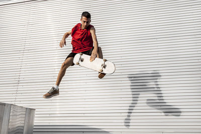 Man with skateboard in mid-air against wall