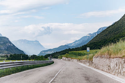 Empty road by mountains against sky