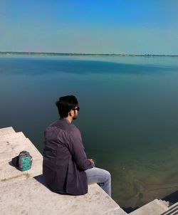 Man looking at view while sitting by sea