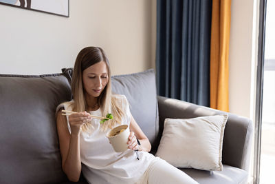 Young woman sitting on sofa at home